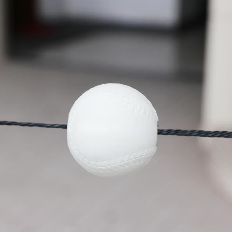Close-up of the baseball threaded on the cord mid-travel
